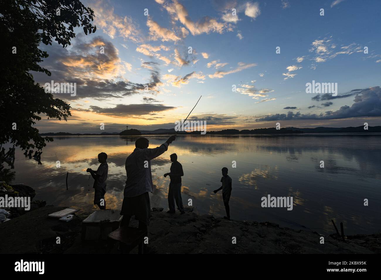 Personnes pêchant dans la rivière Brahmaputra en arrière-plan pendant le coucher du soleil, à Guwahati, Assam, Inde, le mardi 18 août 2020. (Photo de David Talukdar/NurPhoto) Banque D'Images