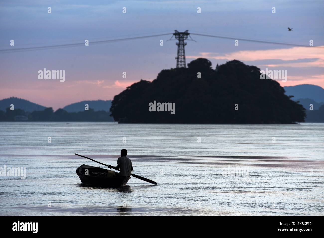Le pêcheur a labouré son bateau dans le fleuve Brahmaputra au coucher du soleil, à Guwahati, Assam, Inde, le dimanche 23 août 2020. (Photo de David Talukdar/NurPhoto) Banque D'Images