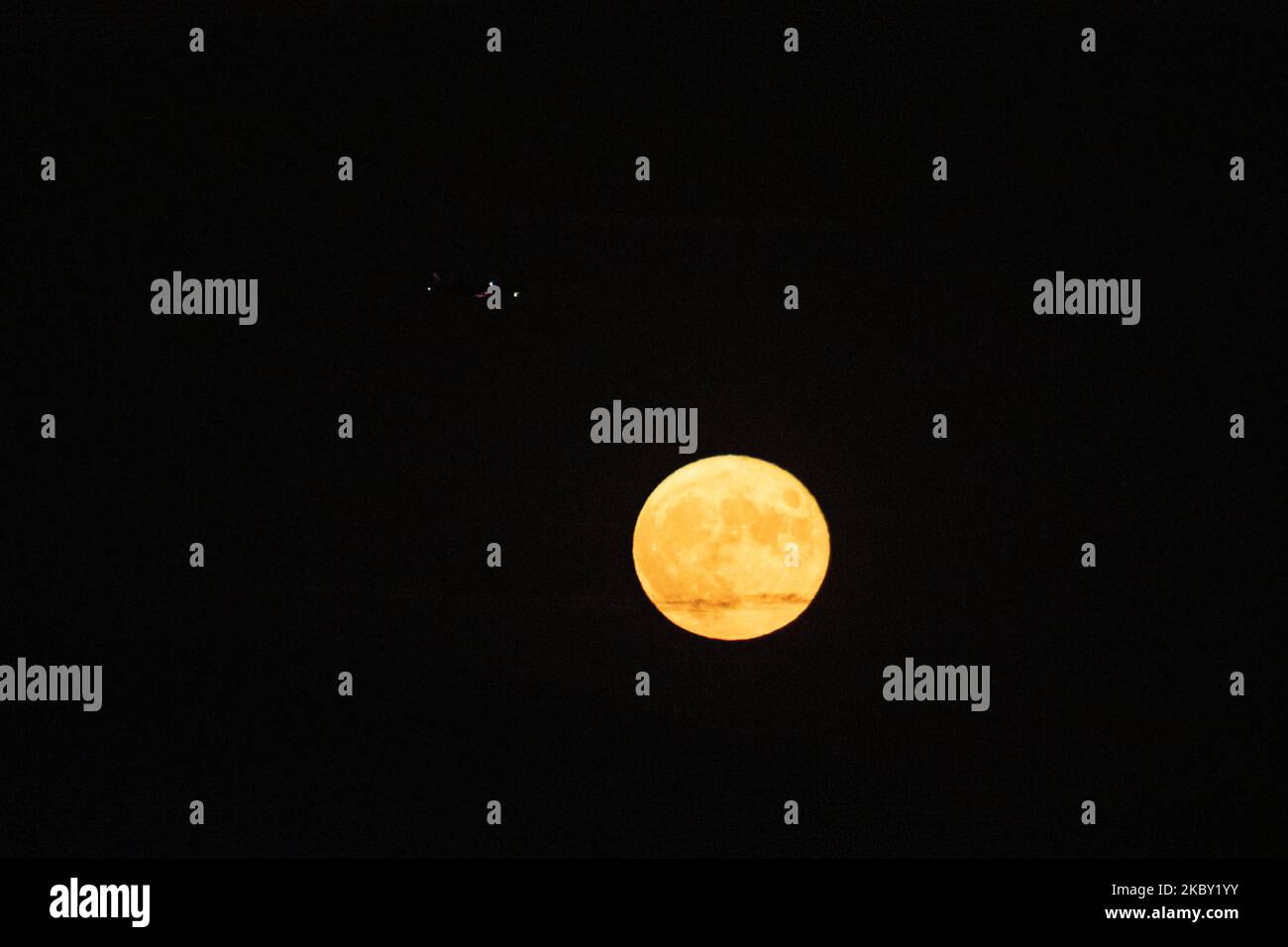 Un avion au-dessus de la lune sur l'approche finale pour l'atterrissage. La pleine Lune de maïs vue derrière la montagne Hortiatis au-dessus de la ville de Thessalonique, dans le nord de la Grèce, capturée de la lagune de Kalochori et du parc national. Le satellite naturel de la Terre, vu de couleur jaune, illumine et crée des réflexions sur l'eau de mer. La phase lunaire, la Lune du maïs se produit tous les trois ans et est également connue sous le nom de Lune des fruits, Lune de l'orge, Lune des fantômes affamés, Binara Pura Pasalosvaka jour du Poya, Lune complète du miel pour les bouddhistes etc Thessalonique, Grèce sur 2 septembre 2020. (Photo de Nicolas Economou/NurPhoto) Banque D'Images