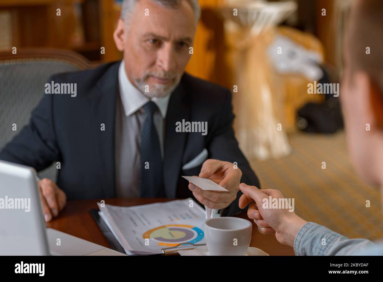 Homme d'affaires donnant sa carte de visite à l'homme tout en dînant dans le restaurant de l'hôtel de luxe Banque D'Images