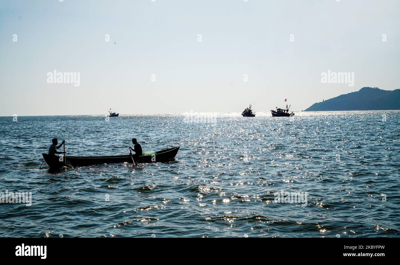 Bateau de pêche avec artisanat et silhouettes de pêcheurs. En arrière-plan sont des bateaux de pêche à moteur à Goa. Le soleil brille dans l'eau - le jour est Banque D'Images