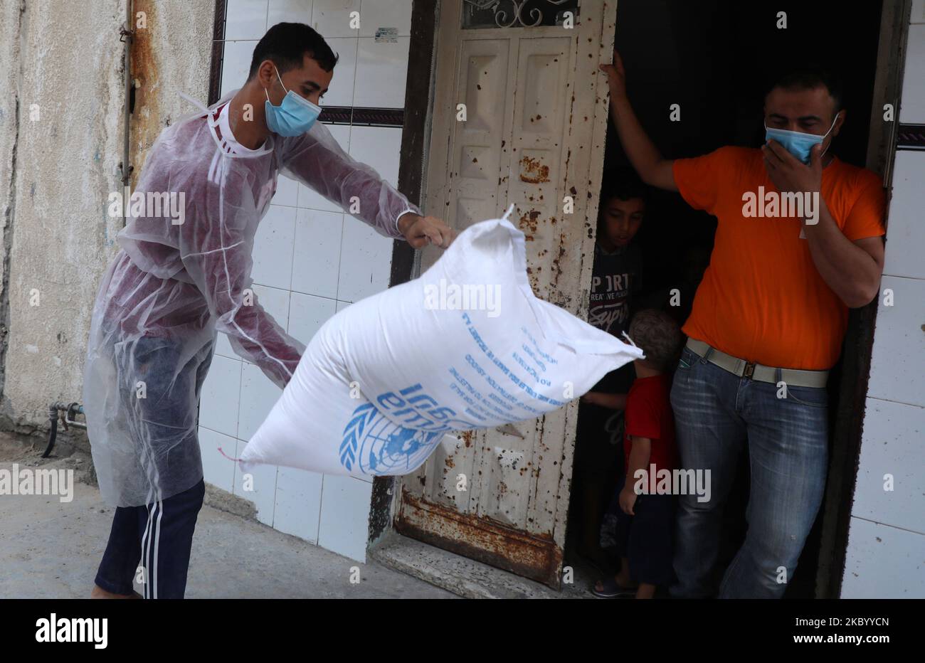 Les travailleurs palestiniens de l'Office de secours et de travaux des Nations Unies pour les réfugiés palestiniens (UNRWA) fournissent des rations d'aide alimentaire aux portes d'un foyer familial de réfugiés plutôt que des distribuer dans un centre des Nations Unies, à Gaza, sur 15 septembre 2020 , en raison de la pandémie COVID-19. (Photo de Majdi Fathi/NurPhoto) Banque D'Images