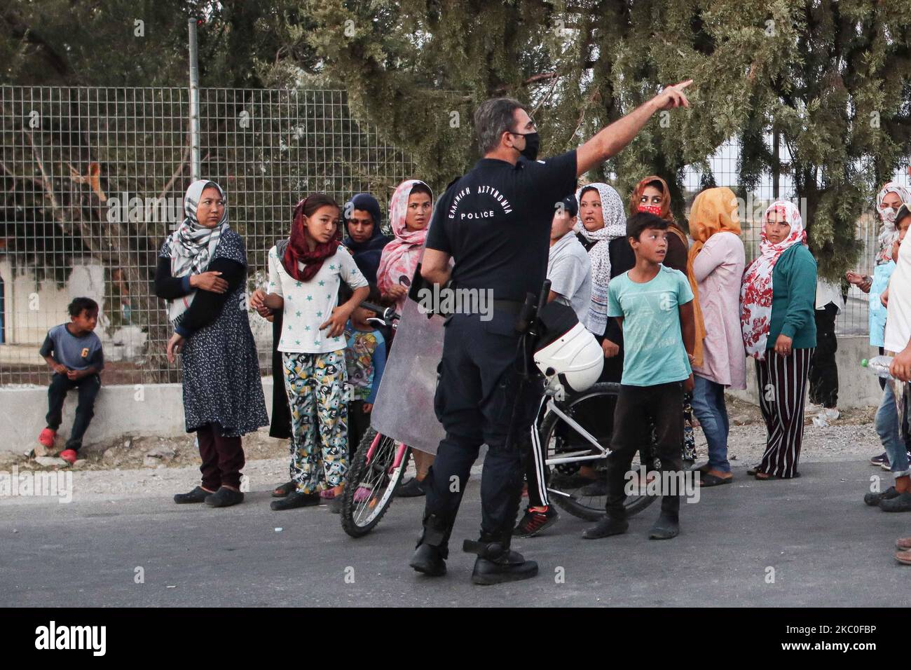 Des femmes de tous âges, de petits enfants, des filles, des adultes et des personnes âgées, sont vues dans la file d'attente demandant et exigeant de la nourriture des policiers. Ces demandeurs d'asile refusent d'entrer et de vivre dans le nouveau camp en espérant qu'ils seront transférés dans un autre pays européen, la plupart d'entre eux étant d'Afghanistan, Ils restent en bord de route dans des camps de fortune entre le nouveau camp de réfugiés de Kara Tepe ou Mavrovouni construit par l'armée grecque avec des tentes du HCR et la ville de Mytilène ( Mitilini ) avec des milliers de réfugiés et de migrants après l'incendie dans le hotspot de Moria, sur 9 septembre 2020. KARE Tepe, île de Lesbos, Grèce on Banque D'Images