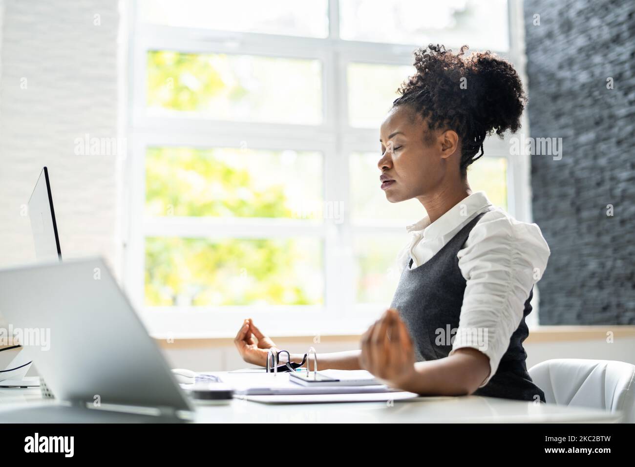 Méditation yoga à la réception. Femme d'affaires africaine américaine Banque D'Images