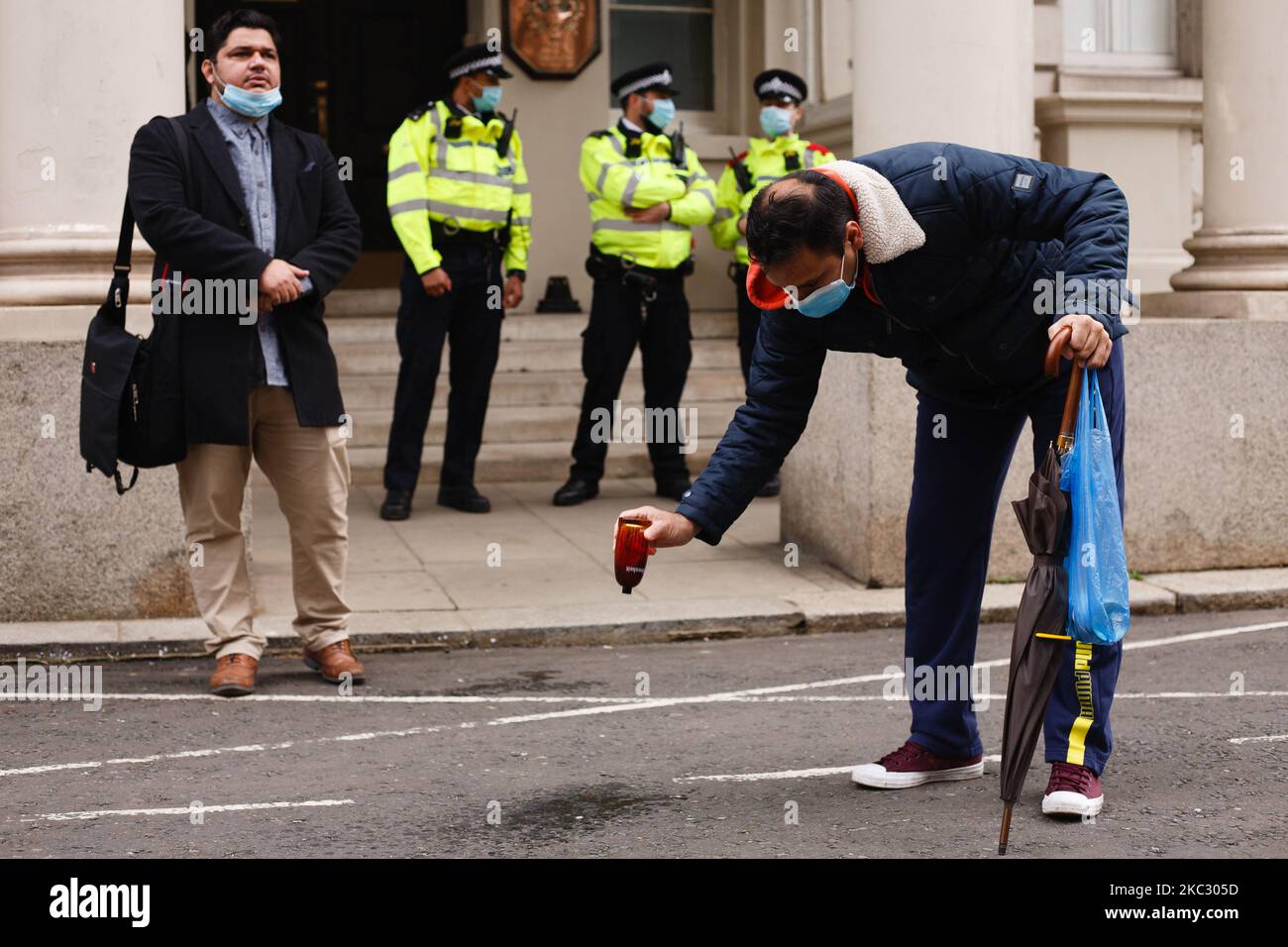 Un homme vide une bouteille de parfum français sur le sol alors que des manifestants s'opposent à la publication en France de dessins animés du prophète Mahomet protestent devant l'ambassade de France à Londres, en Angleterre, sur 30 octobre 2020. Le président français Emmanuel Macron a déployé des milliers de soldats sur des sites tels que des lieux de culte et des écoles à travers la France, à une époque de colère musulmane croissante à travers le monde à la défense du pays du droit de publier les dessins animés, Et après deux avant-postes, à Paris et à Nice, en autant de semaines. (Photo de David Cliff/NurPhoto) Banque D'Images