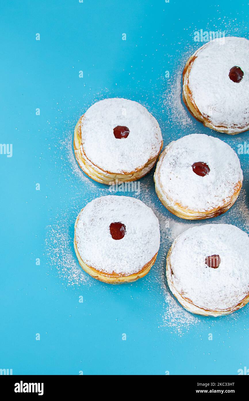 Symboles de la fête religieuse juive Hanukkah.Dessert traditionnel beignets sufganiyot sur fond bleu.Copier l'espace. Banque D'Images