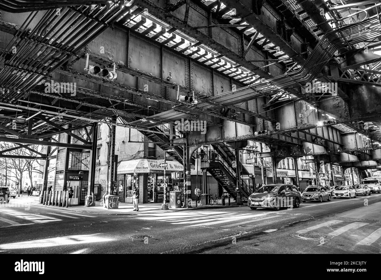 (NOTE DE LA RÉDACTION: L'image a été convertie en noir et blanc) vue de la vie quotidienne de la route et de la rue sous le pont aérien du métro construction métallique des lignes M, J et Z près de la station Marcy Ave, avec des restaurants, des boutiques, la célèbre tranche de dollar pizza, Trafic avec voitures et camions et avec trottoirs dans la rue Broadway à Brooklyn, New York. Brooklyn est le comté le plus peuplé de l'État de New York et le deuxième plus densément peuplé des États-Unis. Brooklyn, NY, États-Unis, le 13 février 2020. (Photo de Nicolas Economou/NurPhoto) Banque D'Images