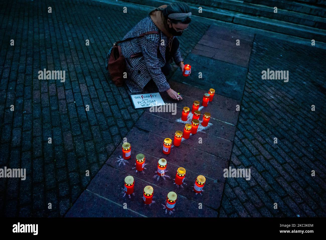 Une femme éclaire une bougie sur un symbole de boulon d'éclairage rouge, lors de la manifestation en solidarité avec les femmes polonaises a eu lieu à Eindhoven, pays-Bas sur 8 novembre 2020. (Photo par Romy Arroyo Fernandez/NurPhoto) Banque D'Images