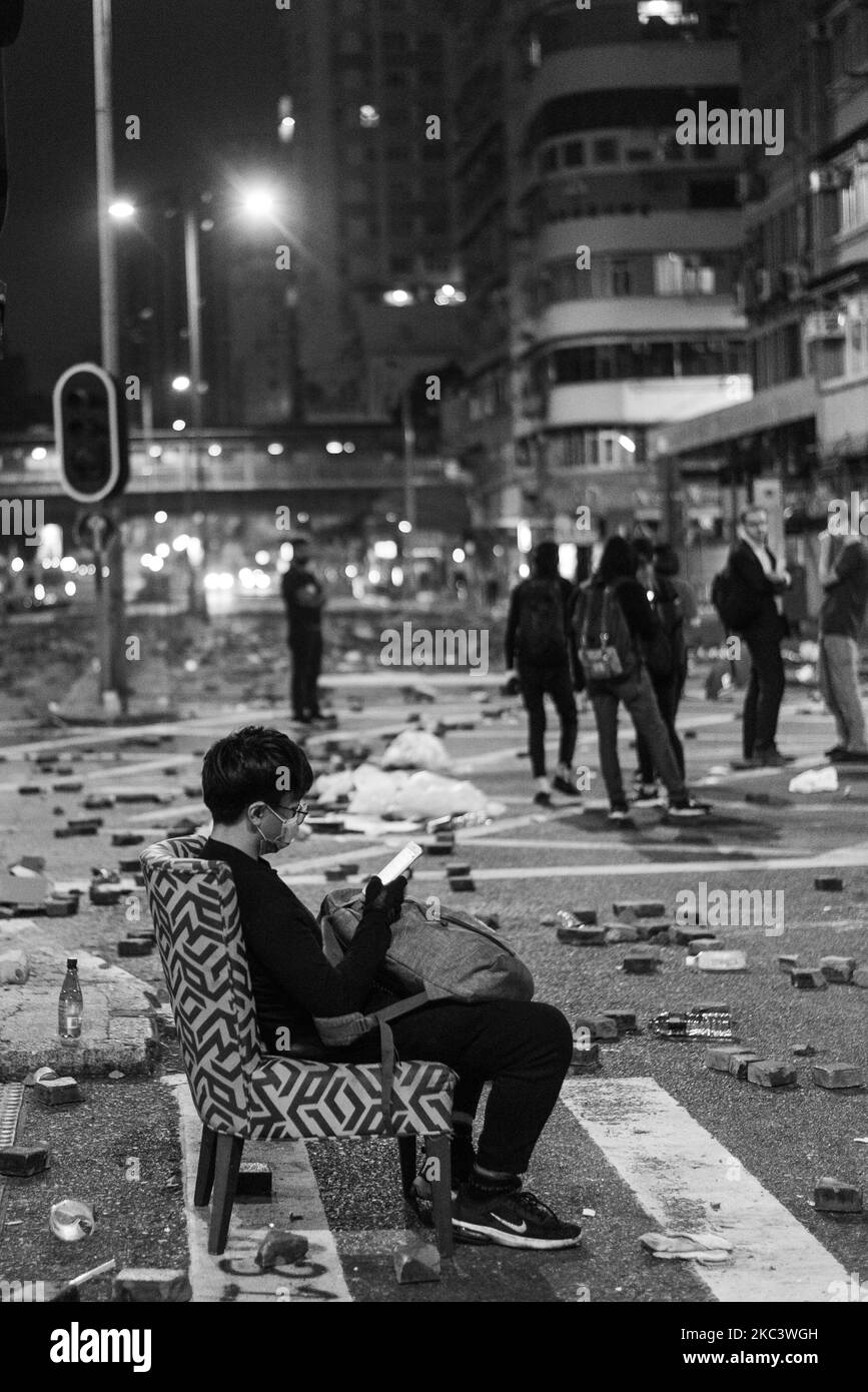 (NOTE DE L'ÉDITEUR: L'image a été convertie en noir et blanc) Un manifestant fatigué vérifie son téléphone sur un fauteuil au milieu d'une intersection sur la rue Argyle. Sur 12 novembre 2019 à Hong Kong, Chine. (Photo de Marc Fernandes/NurPhoto) Banque D'Images