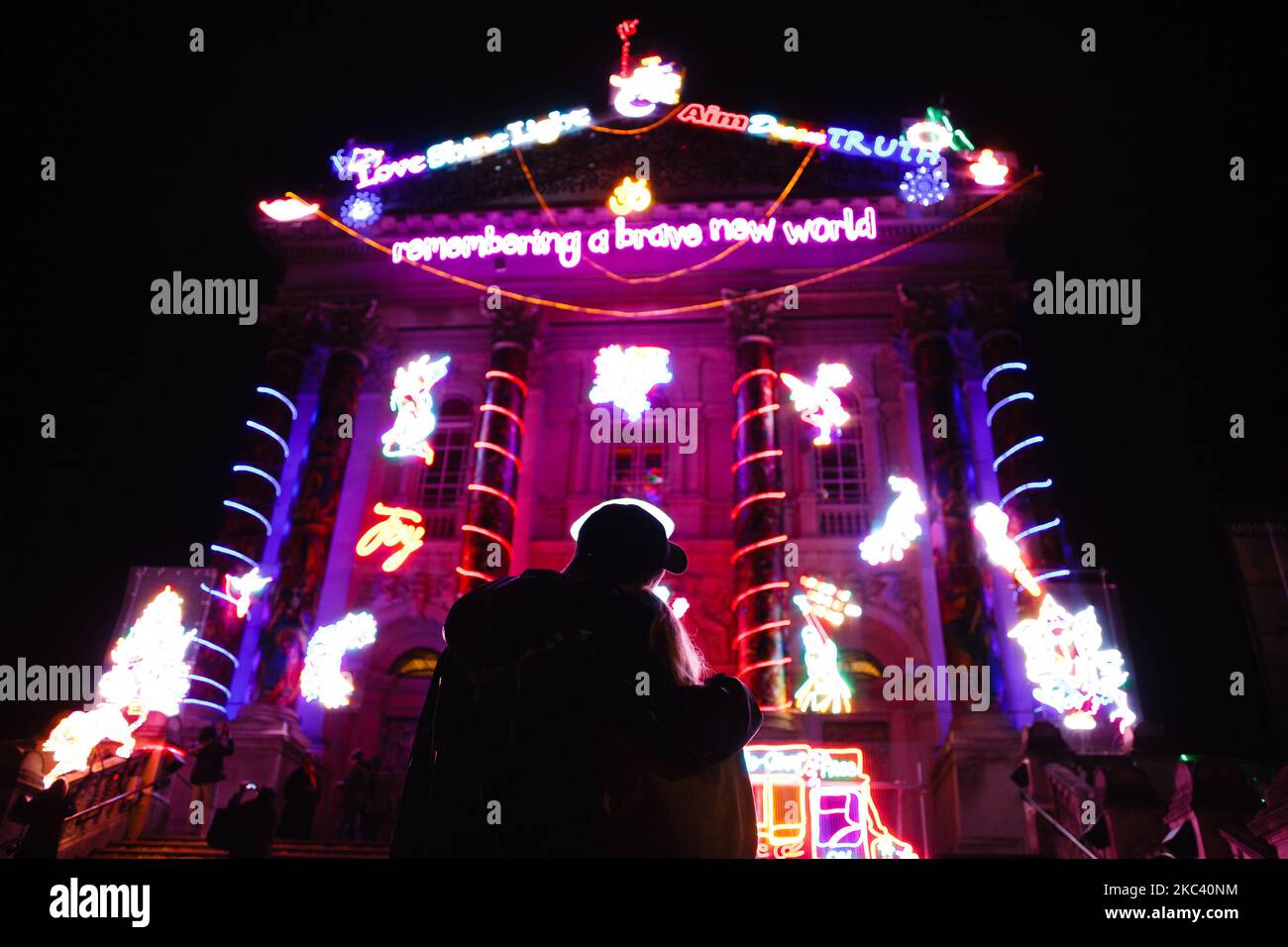 Un couple embrasse sous une installation de lumière de néon « se souvenir D'Un nouveau monde brave », par l'artiste britannique Chila Kumari Singh Burman, qui couvre la façade de la galerie d'art Tate Britain à Londres, en Angleterre, sur 13 novembre 2020. L'œuvre, qui combine la mythologie hindoue, l'imagerie Bollywood, l'histoire coloniale et les souvenirs personnels (y compris la fourgonnette glacée de la famille Burman), forme la quatrième commission annuelle d'hiver à la galerie et a été dévoilée aujourd'hui, à la veille de Diwali, le festival indien des lumières. L'installation sera en place jusqu'à 31 janvier l'année prochaine. (Photo de David Cliff/NurPhoto Banque D'Images