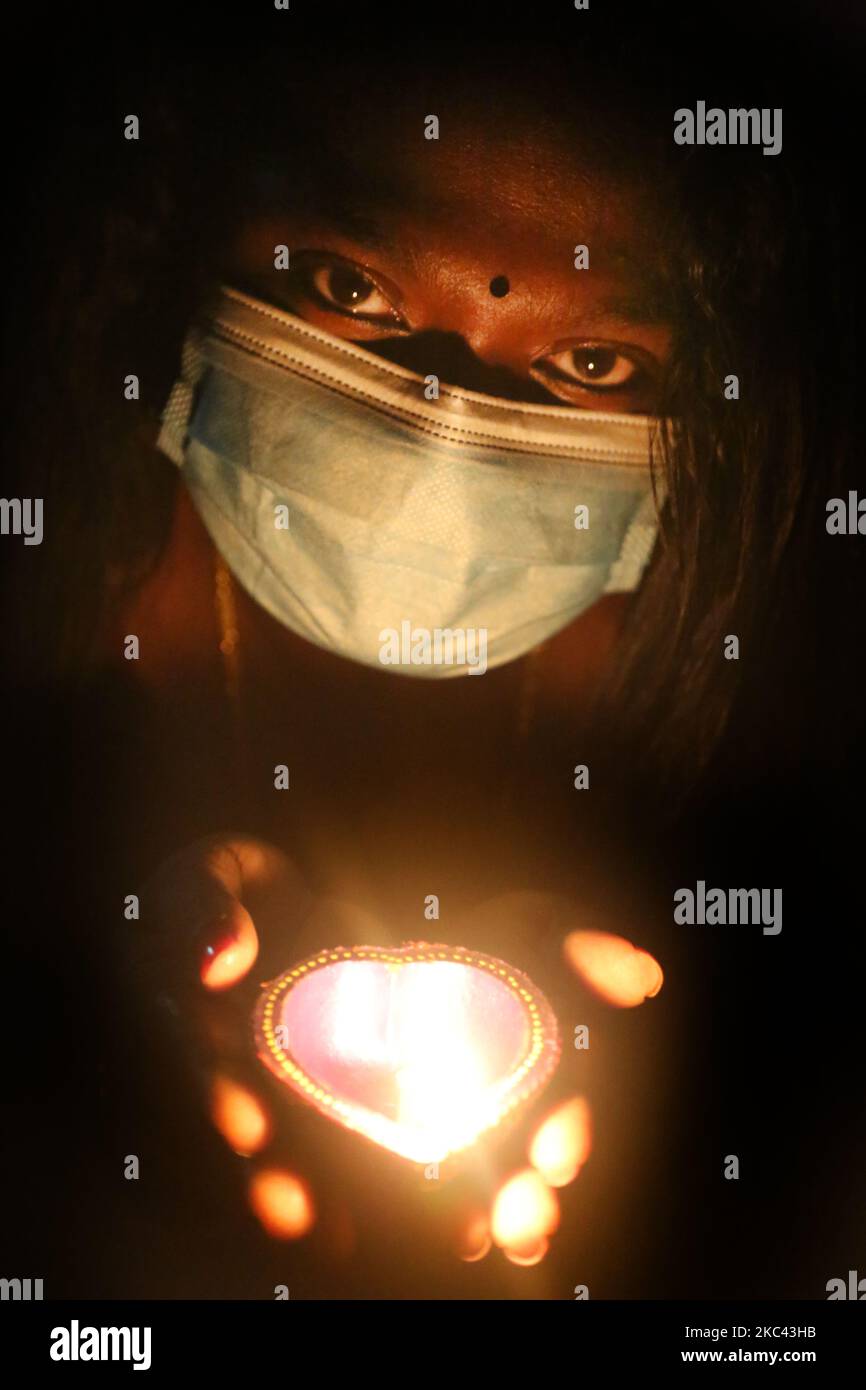 Femme hindoue portant un masque facial pour la protéger du nouveau coronavirus (COVID-19), alors qu'elle détient une diya (petite lampe en argile) pendant le festival de Diwali à un temple hindou à Toronto, Ontario, Canada, on 14 novembre 2020. (Photo de Creative Touch Imaging Ltd./NurPhoto) Banque D'Images