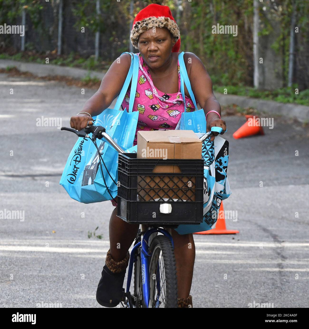 Une femme à vélo transporte de la nourriture offerte par la deuxième Harvest Food Bank du centre de la Floride et la ville d'Orlando lors d'un événement de distribution de nourriture à l'école secondaire Jones sur 20 novembre 2020 à Orlando, en Floride. Avec l'approche de Thanksgiving, des milliers de familles de la région d'Orlando ont besoin d'aide alimentaire en raison de licenciements massifs dans les parcs thématiques locaux et l'industrie touristique. (Photo de Paul Hennessy/NurPhoto) Banque D'Images