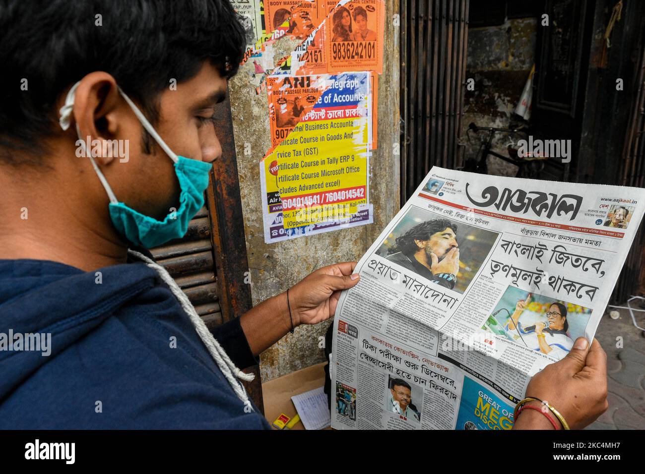 Un garçon portant un masque lit les nouvelles de la mort soudaine de Diego  Maradona dans un journal. La superstar du football de 60 ans est décédée  après avoir succombé à un