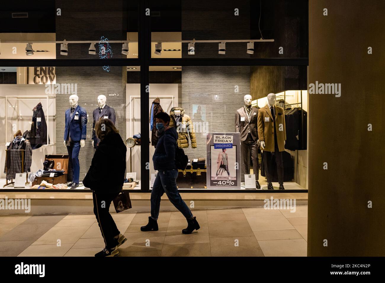 Les gens se promènant à travers les fenêtres du magasin avec des panneaux de réduction affichés sur 26 novembre au village des Pouilles à Molfetta. Le Black Friday est attendu depuis longtemps cette année avec ses réductions folles mais, compte tenu de la pandémie en cours, de nombreux magasins fermés, des restrictions de temps et très peu de personnes autour de lui est vraiment noir. Puglia, étant une zone orange, il est interdit de se déplacer d'une ville à une autre, donc les acheteurs possibles deviennent peu. (Photo par Davide Pischettola/NurPhoto) Banque D'Images