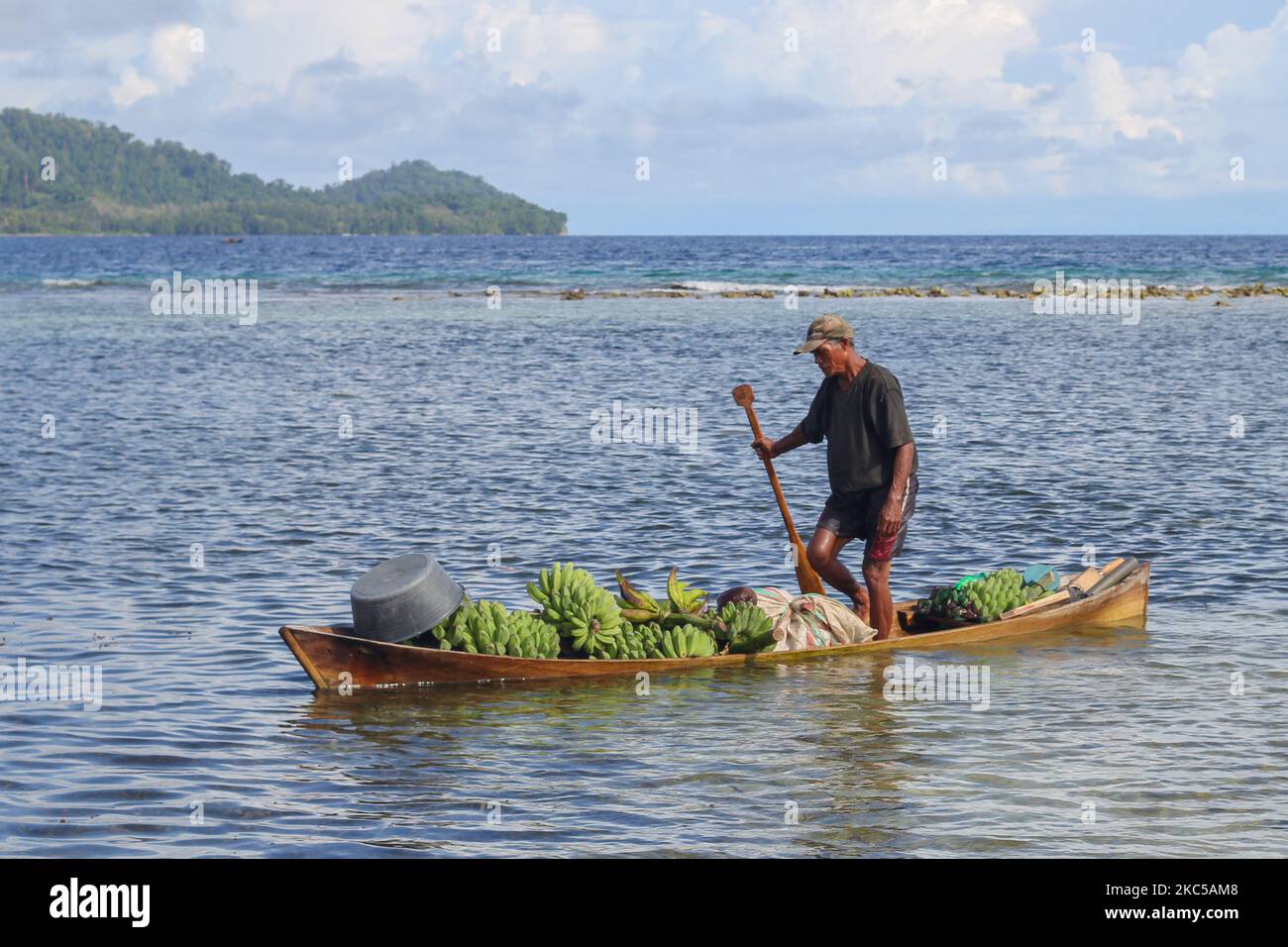 Un pêcheur apporte des bananes qui remplissent son petit bateau sur la plage. Nord de Maluku, Indonésie : 15 juillet 2017. Banque D'Images