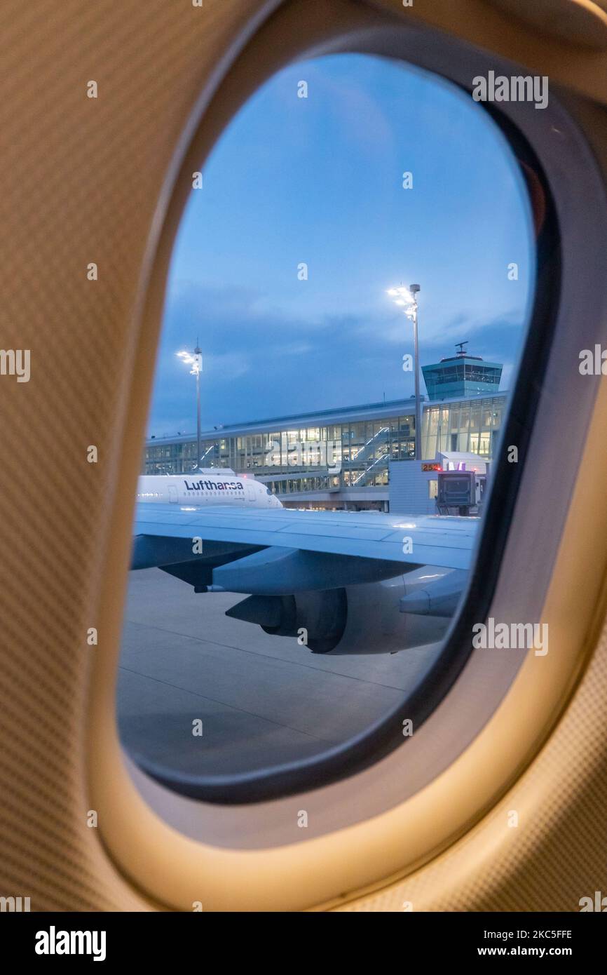 Lufthansa Airbus A350 et le terminal de l'aéroport comme vu tôt le matin à l'aube, heure de lever du soleil depuis une autre fenêtre d'avion, garés aux portes de l'aéroport international de Munich EDDM MUC. L'avion de A359 ou A350-900 passagers à carrosserie large, moderne et évolué, porte le nom d'Ulm et est équipé de 2x moteurs RR. Deutsche Lufthansa AG DLH ou LH est la plus grande compagnie aérienne d'Allemagne avec une base centrale à l'aéroport de Francfort, Munich et Berlin, ancien transporteur de drapeau allemand et membre fondateur du groupe d'aviation de Star Alliance. La circulation mondiale des passagers a diminué durant toute la durée Banque D'Images