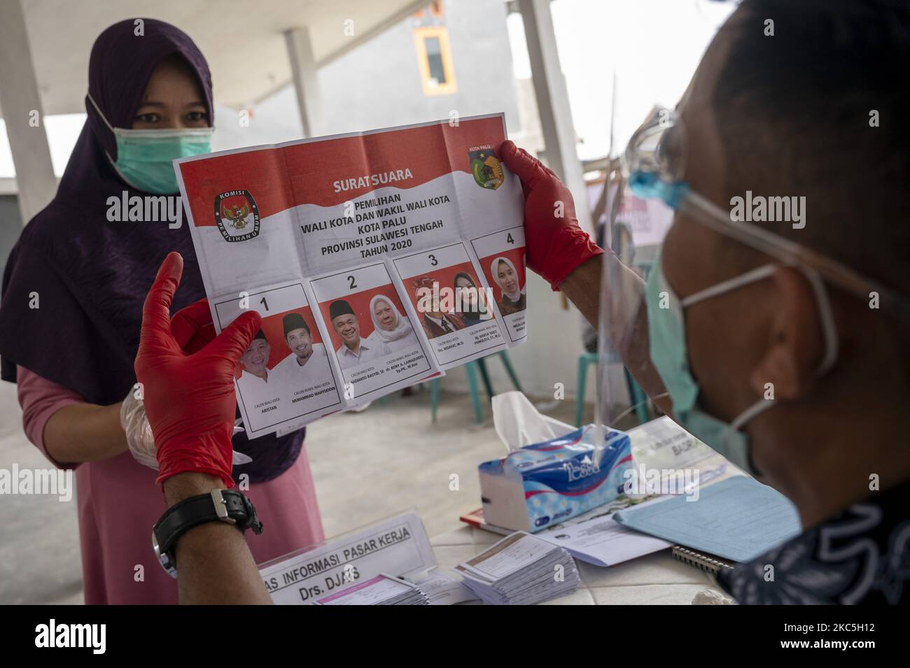 Un officier présente un nouveau bulletin de vote à un électeur lors d'une élection simultanée à la station de vote 08, village de Palupi, ville de Palu, province centrale de Sulawesi, Indonésie sur 9 décembre 2020. La province centrale de Sulawesi procède simultanément à l'élection du gouverneur/sous-gouverneur et de sept chefs régionaux au niveau du régent et du maire. Les élections simultanées ont également eu lieu dans 270 régions, soit 9 provinces, 224 régences et 37 villes dans toute l'Indonésie. (Photo de Basri Marzuki/NurPhoto) Banque D'Images