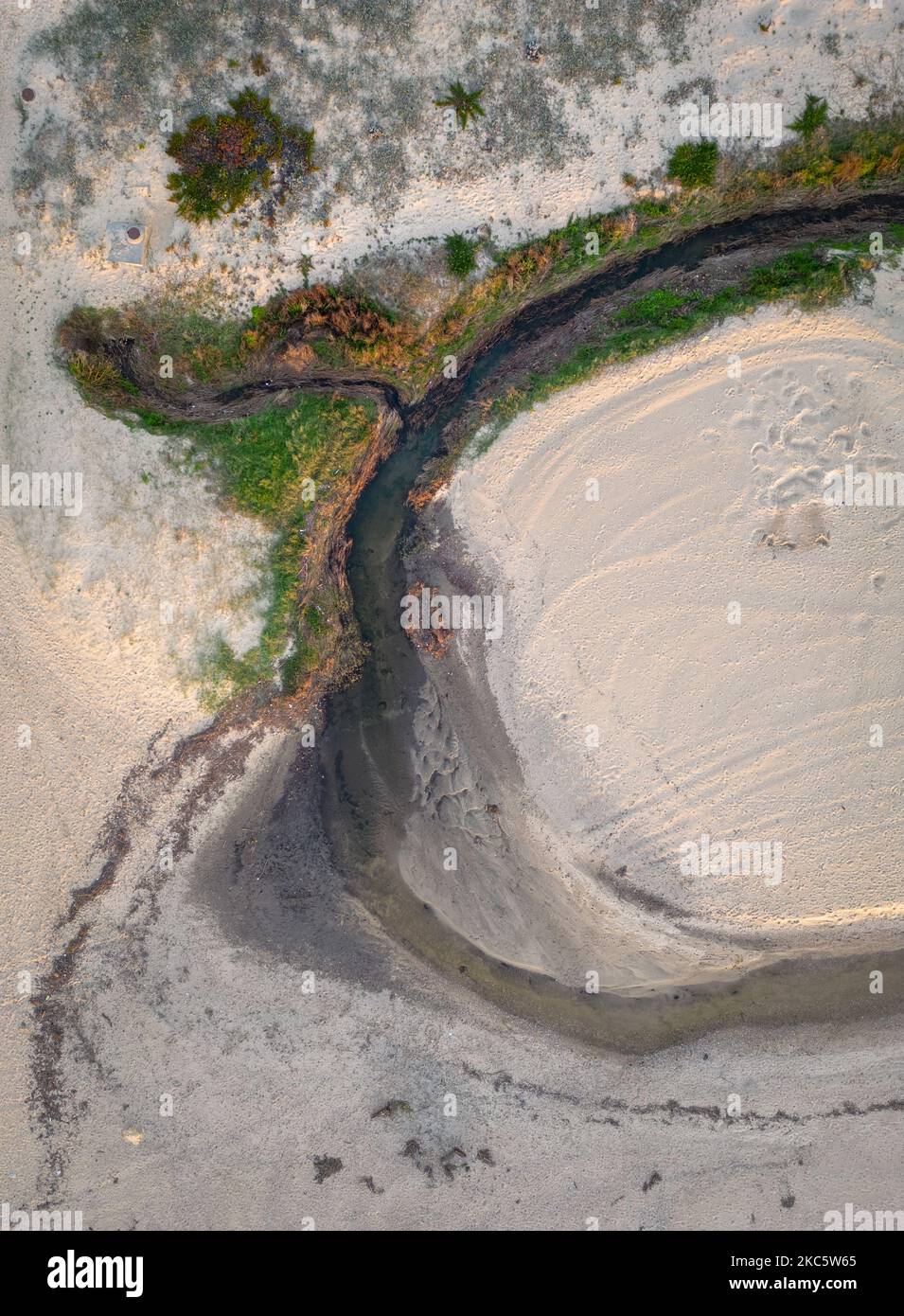 Petit ruisseau de rivière qui coule à l'océan à travers une plage de sable Banque D'Images