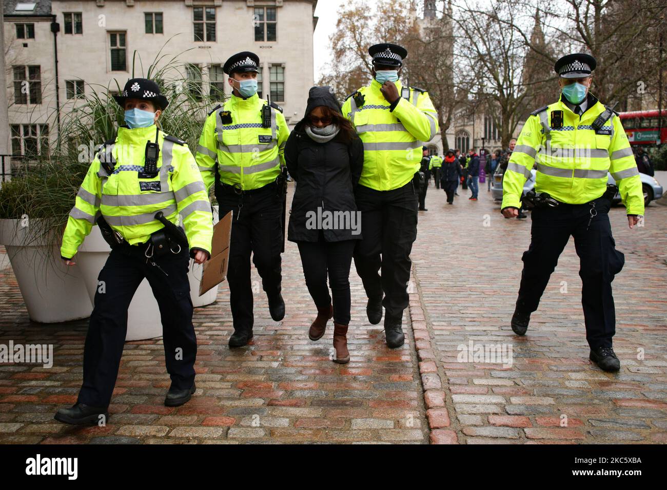 Une militante protestant contre les restrictions d'isolement du coronavirus et toute vaccination obligatoire contre le covid-19 est arrêtée par des policiers dans la rue Victoria à Londres, en Angleterre, sur 14 décembre 2020. Londres doit être mutée vers les restrictions de niveau 3, indiquant un niveau d'alerte de coronavirus très élevé, à partir de ce mercredi, exigeant la fermeture de pubs, bars, cafés et restaurants autres que d'offrir un service de livraison et de plats à emporter. La ville a été retournée au niveau 2, ou alerte « élevée », restrictions à la fin de la période de quatre semaines de confinement à l'échelle de l'Angleterre sur 2 décembre, avec toutefois quelques dispositions de renforcement ont été Banque D'Images