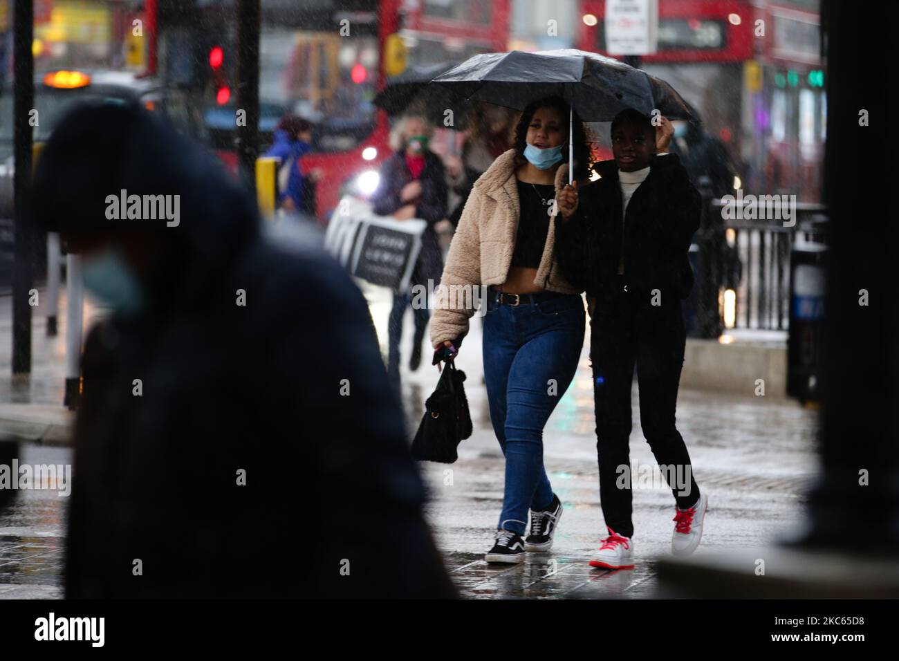 Les femmes se réfugient sous un parapluie lors d'une descente au cirque d'Oxford à Londres, en Angleterre, sur 19 décembre 2020. Londres et de grandes parties du sud-est de l'Angleterre seront placées sous une nouvelle 'Tier 4' de restrictions de coronavirus à partir de minuit ce soir, a annoncé le Premier ministre britannique Boris Johnson cet après-midi, répondre aux préoccupations des autorités au sujet de la propagation d'une souche plus infectieuse du coronavirus qui, semble-t-il, entraîne des hospitalisations dans ces régions du pays. Selon les règles du niveau 4, les magasins non essentiels doivent fermer, tout comme les coiffeurs, les bars à ongles, les salles de gym et les loisirs Banque D'Images