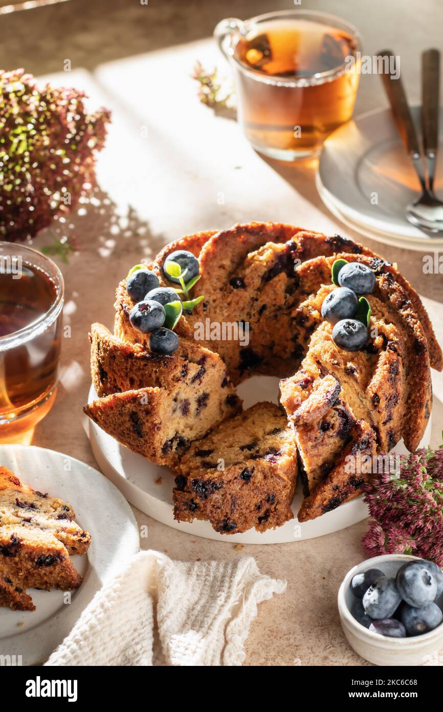 Gâteau aux myrtilles en tranches décoré de baies et de thé, concept de petit déjeuner festif ensoleillé le matin, temps de thé Banque D'Images