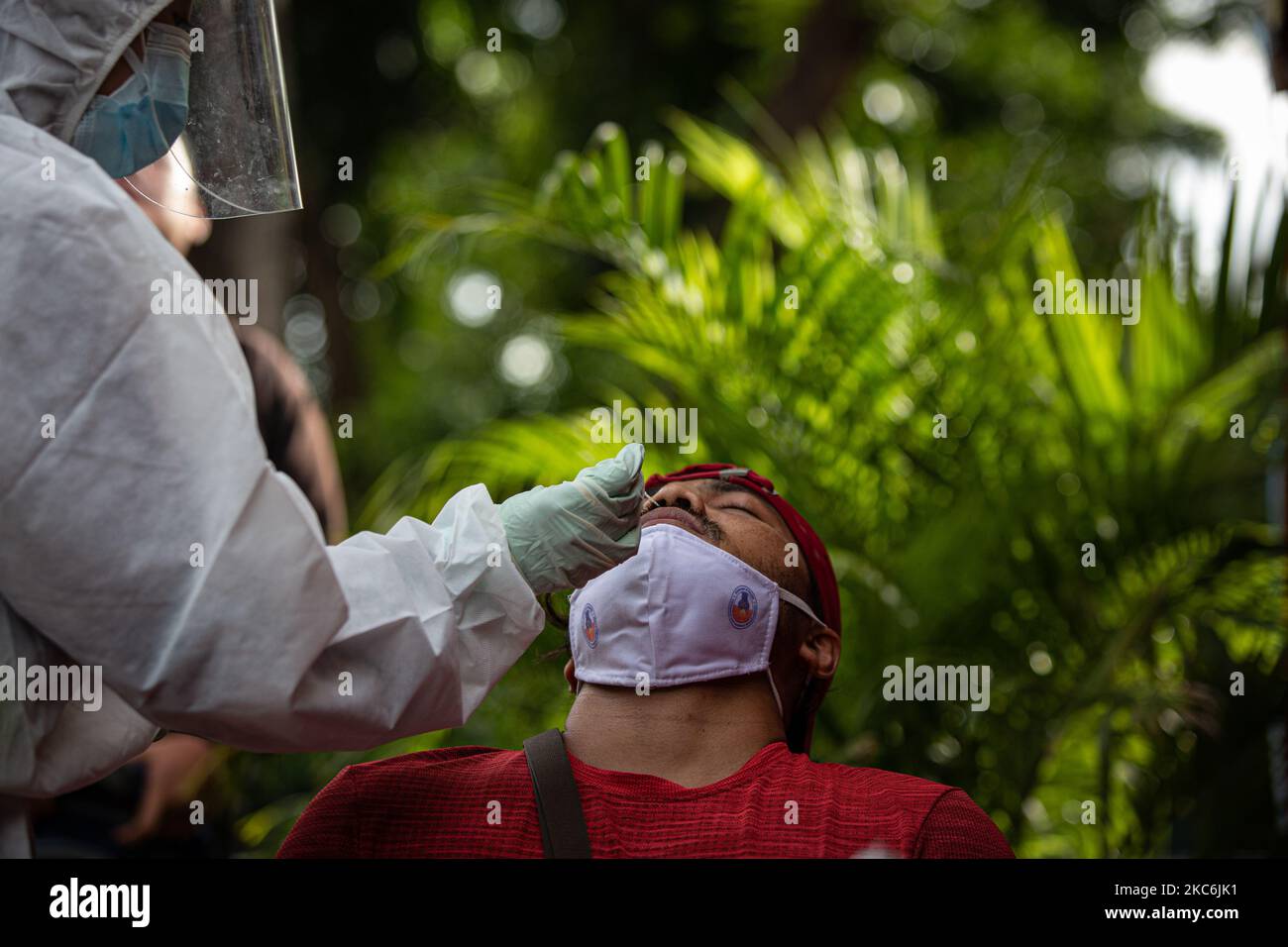 Un professionnel de la santé indonésien prélève un écouvillon auprès de personnes vivant chez un piéton lors des opérations Humanity à Jakarta, Indonésie, le 29 décembre 2020. Selon les données publiées par le Ministère de la santé, l'Indonésie a enregistré plus de sept cent mille cas de COVID-19 depuis le début de la pandémie. Le gouvernement indonésien fermera ses frontières à tous les visiteurs étrangers du 01 au 14 janvier 2021 afin de lutter contre la propagation de la maladie infectieuse. (Photo par Afriadi Hikmal/NurPhoto) Banque D'Images