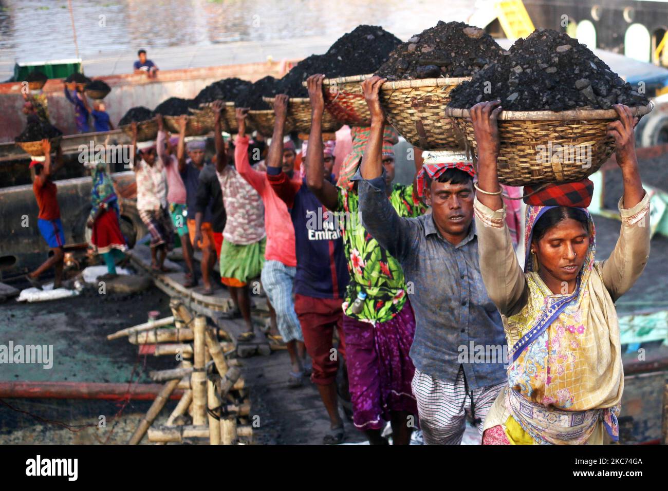 Les travailleurs transportent du charbon sur des paniers lorsqu'ils déchargent ces produits d'un cargo sur la rive du fleuve Buriganga à Dhaka, au Bangladesh, vendredi, au 08 janvier 2021. La consommation actuelle de charbon pour la production d'électricité est d'environ 3,5 millions de tonnes par an pour les deux centrales à charbon du Bangladesh, l'une à Barapukuria (440MW) à Dinajpur et l'autre est la nouvelle centrale Payra (660MW) à Patuakhali. Selon le rapport des médias, si le Plan directeur du secteur de l'énergie 2016 est mis en œuvre, la consommation de charbon pour la production d'électricité serait 10 fois plus en 2030 et 20 fois plus en 2041 que le rp Banque D'Images Les travailleurs transportent du charbon sur des paniers lorsqu'ils déchargent ces produits d'un cargo sur la rive du fleuve Buriganga à Dhaka, au Bangladesh, vendredi, au 08 janvier 2021. La consommation actuelle de charbon pour la production d'électricité est d'environ 3,5 millions de tonnes par an pour les deux centrales à charbon du Bangladesh, l'une à Barapukuria (440MW) à Dinajpur et l'autre est la nouvelle centrale Payra (660MW) à Patuakhali. Selon le rapport des médias, si le Plan directeur du secteur de l'énergie 2016 est mis en œuvre, la consommation de charbon pour la production d'électricité serait 10 fois plus en 2030 et 20 fois plus en 2041 que le rp Banque D'Images
