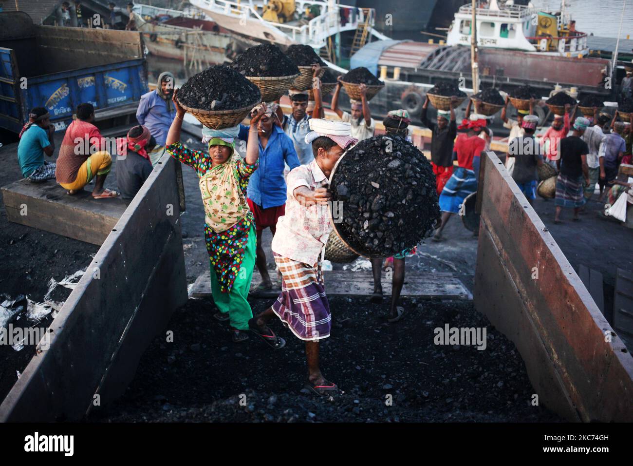 Les travailleurs transportent du charbon sur des paniers lorsqu'ils déchargent ces produits d'un cargo sur la rive du fleuve Buriganga à Dhaka, au Bangladesh, vendredi, au 08 janvier 2021. La consommation actuelle de charbon pour la production d'électricité est d'environ 3,5 millions de tonnes par an pour les deux centrales à charbon du Bangladesh, l'une à Barapukuria (440MW) à Dinajpur et l'autre est la nouvelle centrale Payra (660MW) à Patuakhali. Selon le rapport des médias, si le Plan directeur du secteur de l'énergie 2016 est mis en œuvre, la consommation de charbon pour la production d'électricité serait 10 fois plus en 2030 et 20 fois plus en 2041 que le rp Banque D'Images Les travailleurs transportent du charbon sur des paniers lorsqu'ils déchargent ces produits d'un cargo sur la rive du fleuve Buriganga à Dhaka, au Bangladesh, vendredi, au 08 janvier 2021. La consommation actuelle de charbon pour la production d'électricité est d'environ 3,5 millions de tonnes par an pour les deux centrales à charbon du Bangladesh, l'une à Barapukuria (440MW) à Dinajpur et l'autre est la nouvelle centrale Payra (660MW) à Patuakhali. Selon le rapport des médias, si le Plan directeur du secteur de l'énergie 2016 est mis en œuvre, la consommation de charbon pour la production d'électricité serait 10 fois plus en 2030 et 20 fois plus en 2041 que le rp Banque D'Images
