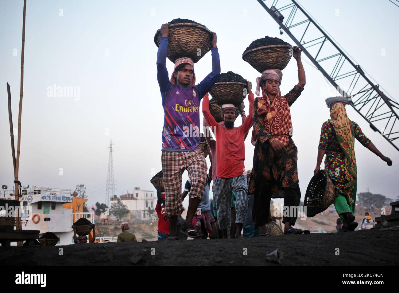 Les travailleurs transportent du charbon sur des paniers lorsqu'ils déchargent ces produits d'un cargo sur la rive du fleuve Buriganga à Dhaka, au Bangladesh, vendredi, au 08 janvier 2021. La consommation actuelle de charbon pour la production d'électricité est d'environ 3,5 millions de tonnes par an pour les deux centrales à charbon du Bangladesh, l'une à Barapukuria (440MW) à Dinajpur et l'autre est la nouvelle centrale Payra (660MW) à Patuakhali. Selon le rapport des médias, si le Plan directeur du secteur de l'énergie 2016 est mis en œuvre, la consommation de charbon pour la production d'électricité serait 10 fois plus en 2030 et 20 fois plus en 2041 que le rp Banque D'Images Les travailleurs transportent du charbon sur des paniers lorsqu'ils déchargent ces produits d'un cargo sur la rive du fleuve Buriganga à Dhaka, au Bangladesh, vendredi, au 08 janvier 2021. La consommation actuelle de charbon pour la production d'électricité est d'environ 3,5 millions de tonnes par an pour les deux centrales à charbon du Bangladesh, l'une à Barapukuria (440MW) à Dinajpur et l'autre est la nouvelle centrale Payra (660MW) à Patuakhali. Selon le rapport des médias, si le Plan directeur du secteur de l'énergie 2016 est mis en œuvre, la consommation de charbon pour la production d'électricité serait 10 fois plus en 2030 et 20 fois plus en 2041 que le rp Banque D'Images