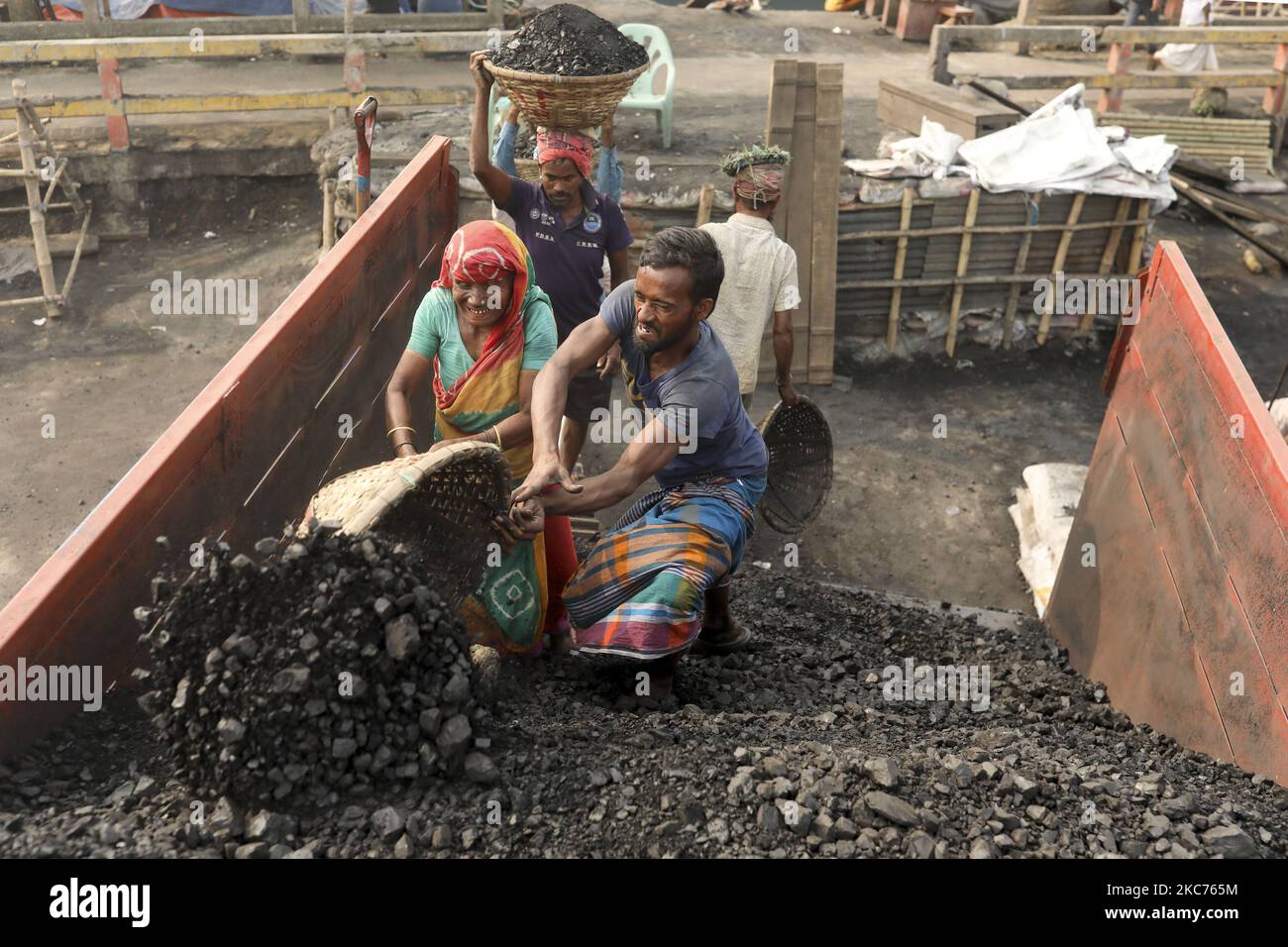 Une main-d'œuvre charbonnière aide une vieille femme à décharger du charbon d'un cargo à Gabtoli, dans la banlieue de Dhaka, sur 09 janvier 2021. Après avoir déchargé 30 paniers de charbon, ils gagnent environ $1 USD. (Photo de Kazi Salahuddin Razu/NurPhoto) Banque D'Images