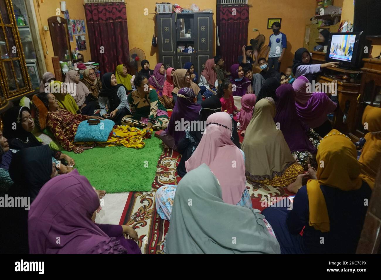 Yusrilanita, la mère d'Indah Halima Putri, une victime de l'accident de la compagnie aérienne Sriwijaya SJ 182 à Jakarta-Pontianak à sa résidence, regarde les nouvelles sur la recherche d'un avion qui s'est écrasé dans la mer des îles Seribu, Jakarta avec des résidents à sa maison, Sungai Pinang II District, Ogan Ilir Regency, Sumatra Sud, le 2021 janvier. (Photo de Sigit Prasetya/NurPhoto) Banque D'Images