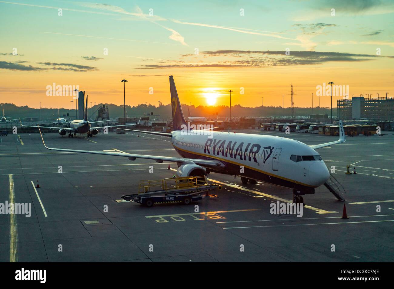 Début de matinée magie heure lever du soleil paysage à Londres Stansted STN EMSS aéroport, avec un avion de Ryanair FR RYR Irish low-cost transporteur, Boeing 737-800 avion garé au tarmac du tablier devant les portes du terminal de l'aéroport. Le trafic mondial de passagers a diminué pendant la pandémie du coronavirus Covid-19 en raison du verrouillage et des restrictions de voyage dans l'industrie aéronautique qui a du mal à survivre en ayant besoin d'aide financière du gouvernement, en demandant aux voyageurs de porter un masque facial, de subir des tests négatifs ou de rester isolés en quarantaine. Aéroport de Stansted, Royaume-Uni sur se Banque D'Images