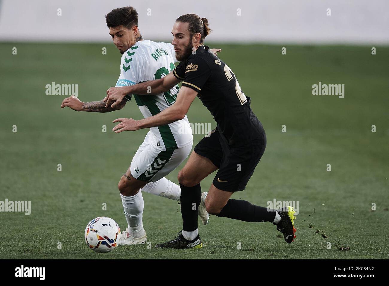 Emiliano Rigoni d'Elche et Oscar Mingueza de Barcelone concourent pour le ballon pendant le match de la Liga Santander entre Elche CF et FC Barcelone à l'Estadio Martinez Valero sur 24 janvier 2021 à Elche, Espagne. Les stades sportifs dans toute l'Espagne restent soumis à des restrictions strictes en raison de la pandémie du coronavirus, car les lois de distanciation sociale du gouvernement interdisent aux fans à l'intérieur des lieux, ce qui entraîne le jeu derrière des portes fermées. (Photo de Jose Breton/Pics action/NurPhoto) Banque D'Images