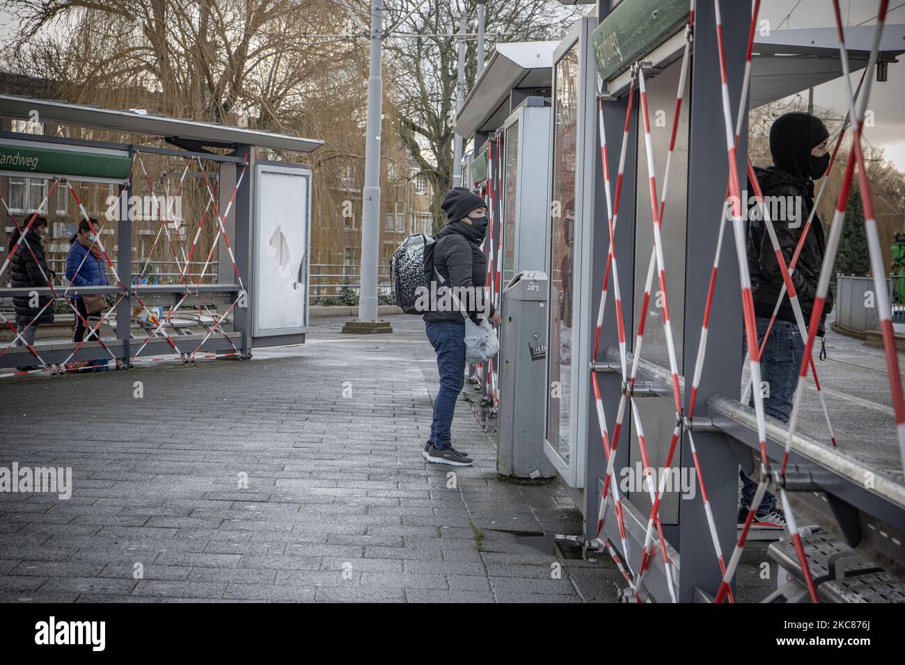 Arrêt de tramway Randweg endommagé vu avec des personnes portant un masque facial. Les conséquences des troubles anti-couvre-feu à Rotterdam. Fenêtres endommagées de magasins, cafés, chaîne de restauration rapide, chaussée détruite, distributeurs de billets cassés, Les arrêts de bus, les arrêts de tramway, les fenêtres et les lunettes endommagées même dans un quartier résidentiel ont été causés par les violents manifestants qui se sont affrontés avec la police et ont pillé le quartier autour de Groene Hilledijk, Beijerlandselaan et Randweg. C'est la nuit consécutive de 3rd émeutes et affrontements avec les politiques après que le gouvernement a imposé le couvre-feu pour lutter contre la propagation de la pandémie a du coronavirus Covid-19 Banque D'Images