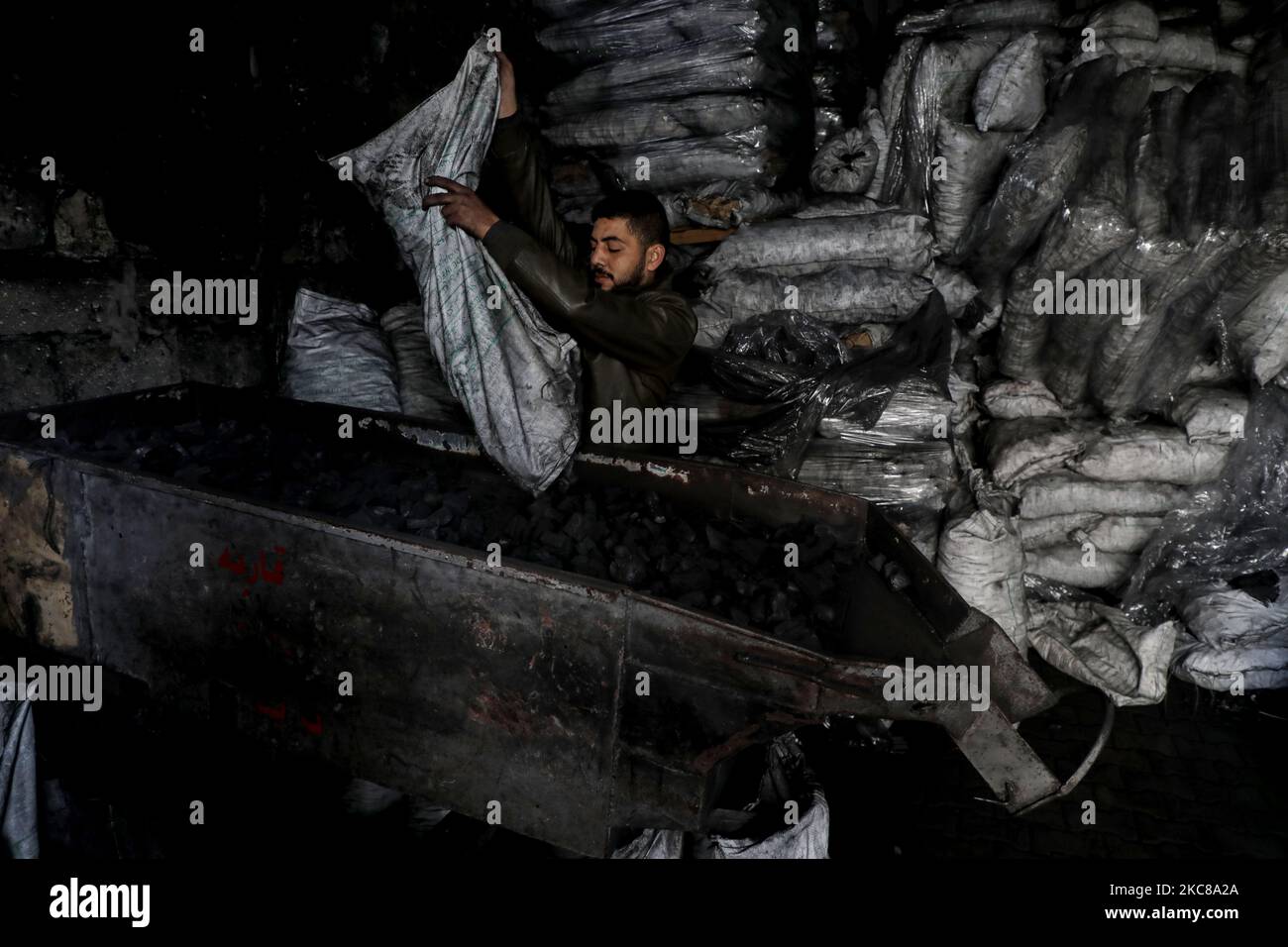 Un travailleur palestinien recueille le charbon de bois qui sera emballé dans des sacs pour le vendre à Jabaliya, dans le nord de la bande de Gaza, le 28 janvier 2021. (Photo de Majdi Fathi/NurPhoto) Banque D'Images