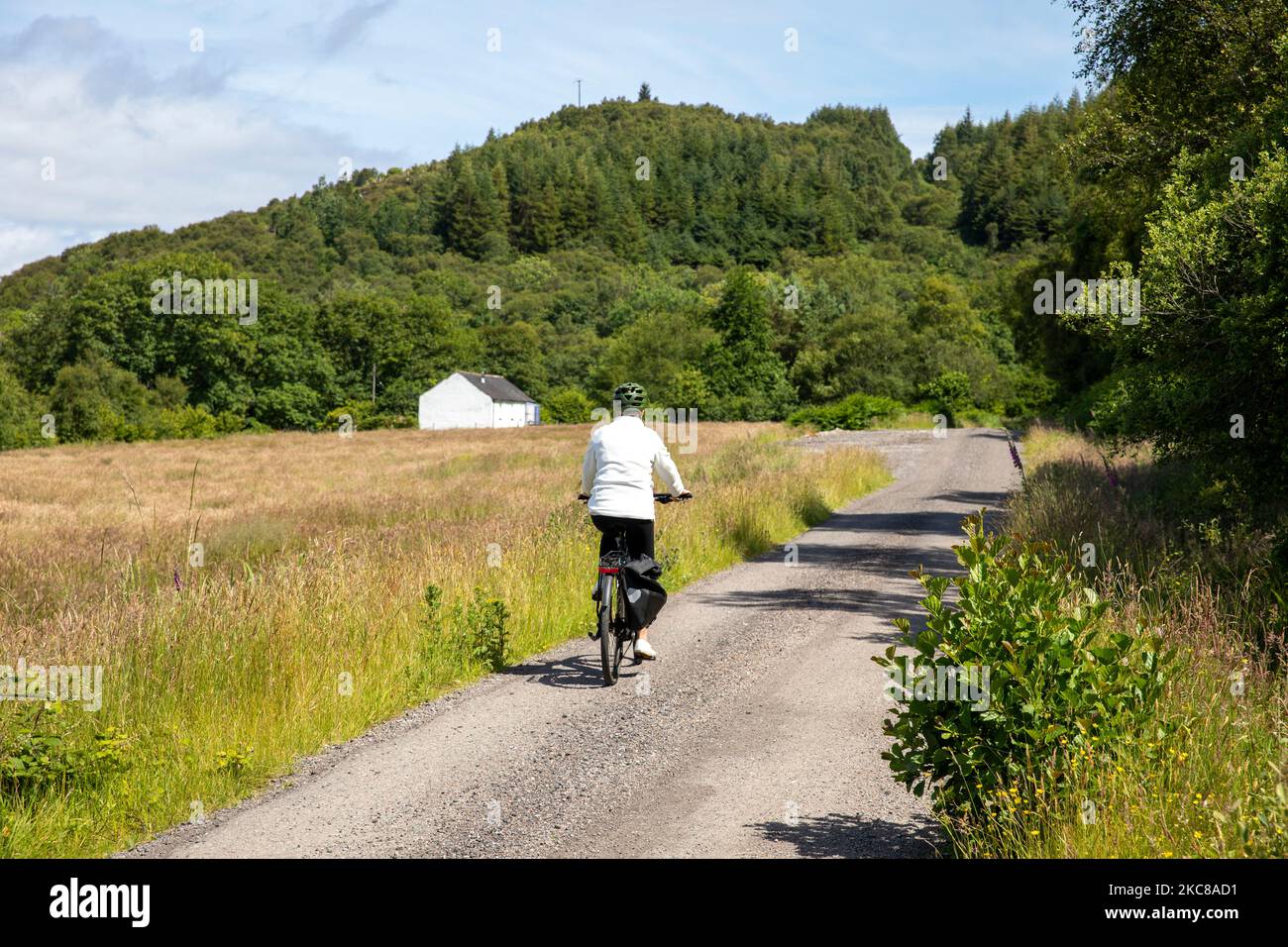 Modèle libéré femme d'âge moyen manèges vélo électrique en Écosse sur la route de vélo de Caledonia Way près d'Oban, Ecosse, Royaume-Uni, été 2022 Banque D'Images