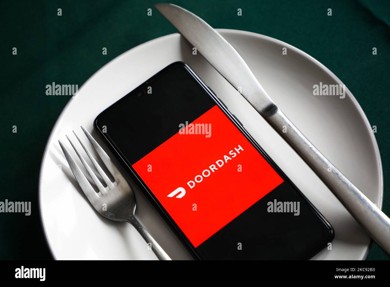 Le logo de l'application Doordash est affiché sur un écran de téléphone mobile photographié pour illustration sur une plaque et avec des couverts. Cracovie, Pologne sur 9 février 2021. Les chiffres montrent que la pandémie de Covid-19 a entraîné une augmentation importante des repas commandés en ligne par le biais d'applications et de sites Web de livraison de nourriture. (Photo d'illustration par Beata Zawrzel/NurPhoto) Banque D'Images