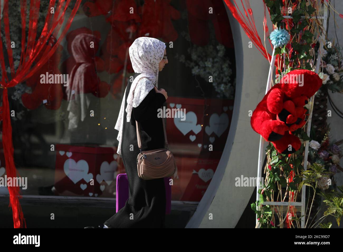 Une femme palestinienne passe devant un magasin où l'on présente des ours rouges le jour de la Saint-Valentin à Gaza, sur 14 février 2021. (Photo de Majdi Fathi/NurPhoto) Banque D'Images