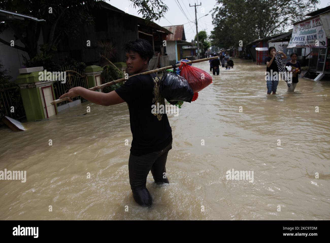 Résidents traversant les inondations dans le sous-district de Pebayuran, régence de Bekasi, ouest de Java, sur 22 février 2021. Des inondations massives ont frappé un certain nombre de villages de Bekasi regency, dans l'ouest de Java, après de fortes pluies qui se sont produites au cours des derniers jours, causant un débordement de la rivière Cibeet l'éclatement du remblai de la rivière Citarum. Au moins 6,000 familles ont été touchées par cette catastrophe. (Photo par Aditya Irawan/NurPhoto) Banque D'Images