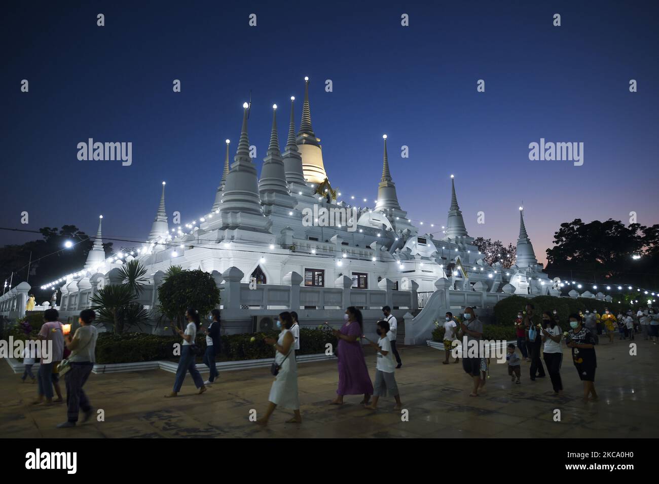 Les personnes qui tiennent des fleurs, des bâtons de jos et des bougies illuminées pour des prières marchent dans un cercle de procession autour du monastère pour marquer la journée de Makha Bucha au temple de Wat Asokaram dans la province de Samut Prakan, Thaïlande, 26 février 2021. (Photo par Anusak Laowilas/NurPhoto) Banque D'Images