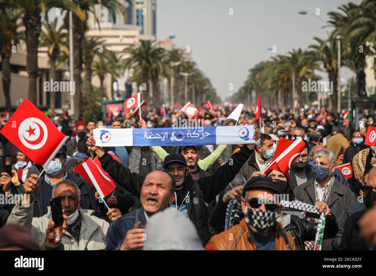 Un partisan lève une bannière d'Ennahda comme d'autres vagues drapeaux de la Tunisie lors d'une manifestation organisée par le parti islamiste d'Ennahda sur l'avenue Mohammed V dans la capitale Tunis, Tunisie, sur 27 février 2021, En faveur de la « légitimité » du Parlement et du gouvernement du premier ministre Hichem Machichi et pour protester contre le rejet par le président Kais Saied du remaniement de Mechichi et pour « protéger la démocratie ». (Photo de Chedly Ben Ibrahim/NurPhoto) Banque D'Images