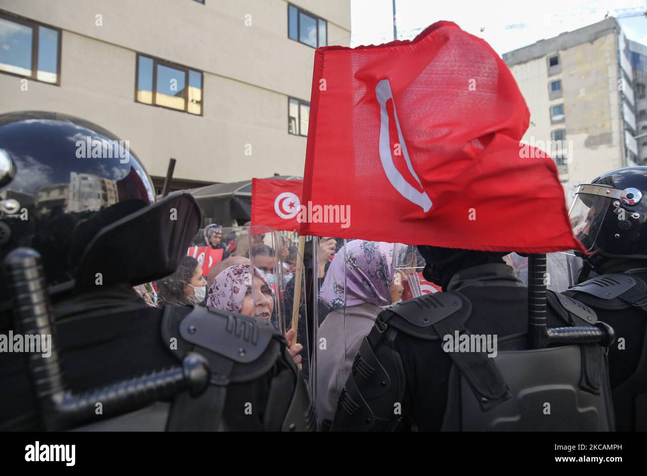 Une manifestante de mouvements islamistes se tient devant les forces de sécurité alors qu'elle lève le drapeau tunisien, lors d'une manifestation devant le siège de la branche tunisienne de l'Union internationale des boursiers musulmans (IUMS) dans la capitale Tunis, Tunisie, sur 10 mars 2021, Pour protester contre le président du Parti du destin libre (PDL), Abir Moussi et ses partisans, qui tiennent un sit-in à l'extérieur du siège de l'IUMS pour en appeler à sa dissolution. (Photo de Chedly Ben Ibrahim/NurPhoto) Banque D'Images