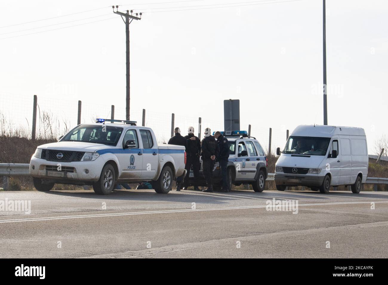 Des voitures de police et des agents de police sont vus en possession de 2 sans-papiers, un d'Afghanistan et un d'Afrique, qui ont franchi illégalement les frontières de la Turquie, sur l'autoroute près de la ville d'Orestiada dans la région d'Evros, Thrace en Grèce. La rivière Evros ou Martisa ou Meric est la frontière extérieure du Sud-est de l'UE et de la zone Schengen. Les demandeurs d'asile sont capturés le long des frontières grecques turques alors qu'ils tentent d'entrer en Grèce et dans l'Union européenne. La police hellénique et les forces de Frontex patrouillent la frontière et capturent quotidiennement, emprisonnent ou arrêtent des migrants, des réfugiés et des passeurs sur le grec - Banque D'Images