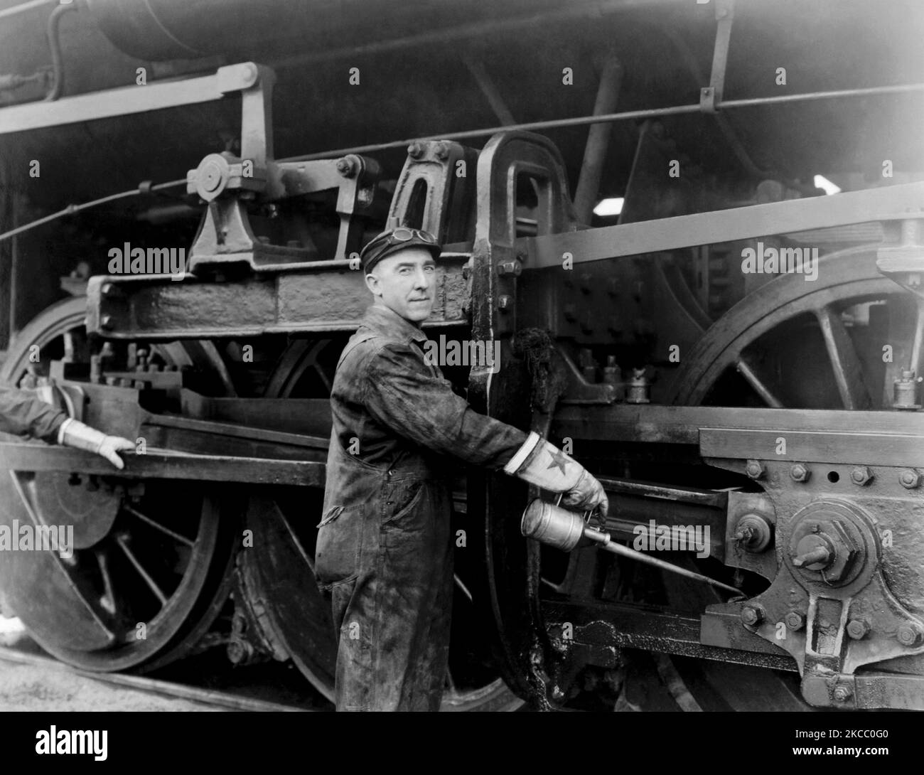 Un mécanicien qui fait le graissage des roues d'une locomotive à vapeur à partir du long nez d'aiguille d'une bureque à huile, vers 1923. Banque D'Images