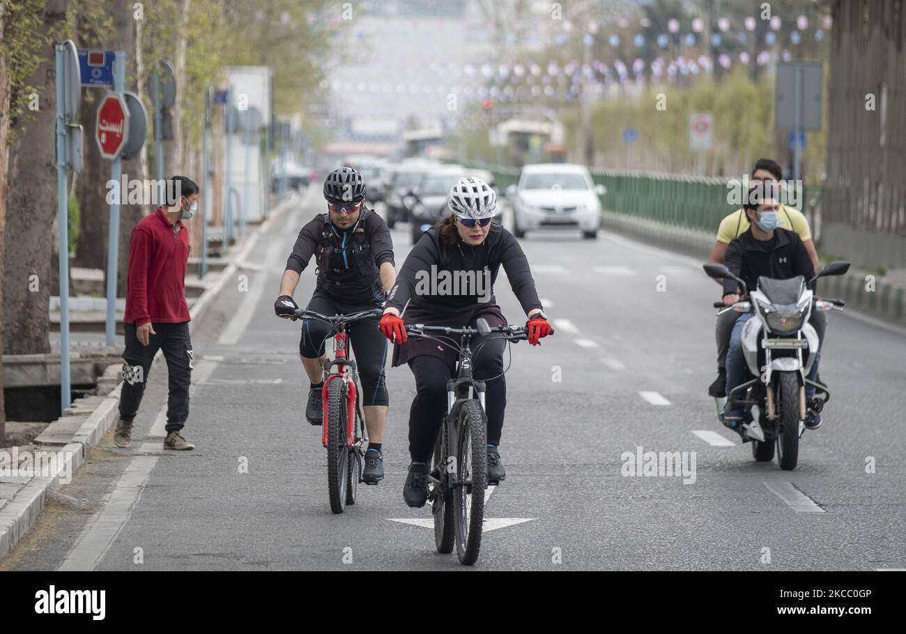 Un iranien et une femme (C) font du vélo le long d’une avenue dans le nord de Téhéran, le jour de Sizdah Bedar, également connu sous le nom de Journée de la nature, à 2 avril 2021. Sizdah Bedar, également connue sous le nom de la Journée de la nature, est un festival iranien qui se tient chaque année le treizième jour de Farvardin (le premier mois du calendrier iranien), où les gens passent du temps à l’extérieur et marquent la fin des vacances de Nowruz en Iran. Mais le gouvernement iranien a fermé les parcs et demandé aux gens de rester chez eux pour se protéger et protéger les autres contre la nouvelle épidémie de coronavirus (COVID-19). (Photo de Morteza Nikoub Banque D'Images