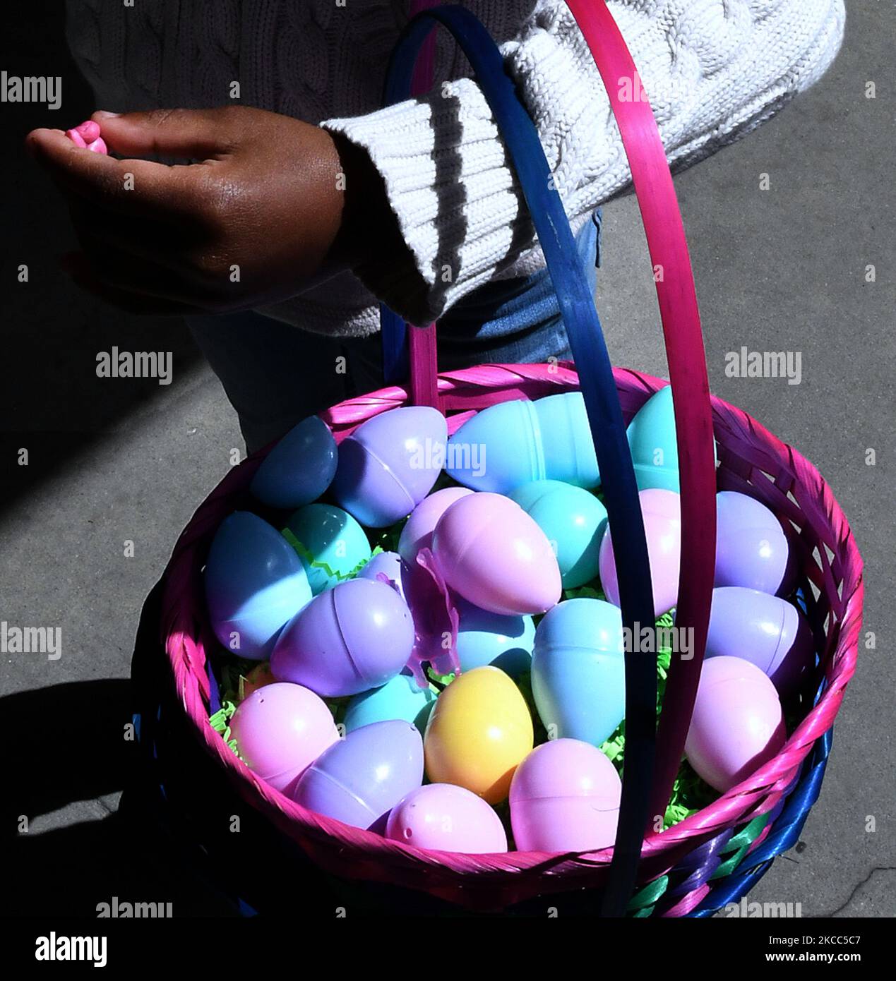 Un enfant porte un panier d'œufs en plastique de couleur qu'il a recueillis  après avoir participé à une chasse aux œufs de Pâques à l'église baptiste  de la rue Delaney, sur 3