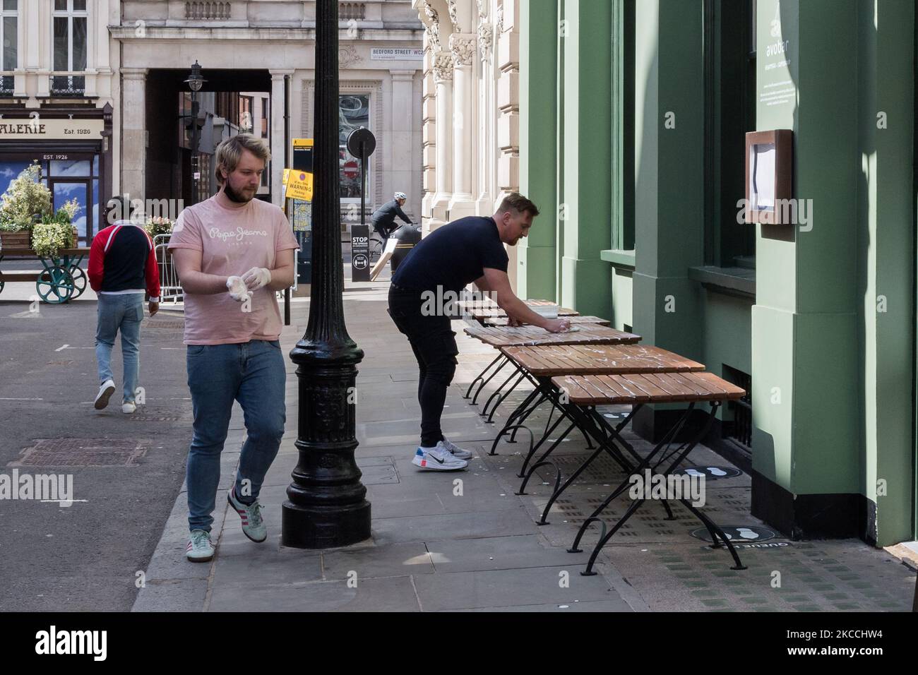 LONDRES, ROYAUME-UNI - 11 AVRIL 2021 : le personnel nettoie les tables devant un bar à Covent Garden alors que les entreprises se mettent à ouvrir leurs locaux à leurs clients dès demain après avoir été fermés pendant plus de trois mois sous le confinement du coronavirus, le 11 avril 2021 à Londres, en Angleterre. À partir du lundi 12 avril, la prochaine étape de la levée des restrictions de verrouillage va de l'avant avec des pubs et des restaurants autorisés à servir de la nourriture et des boissons à l'extérieur, l'ouverture de magasins non essentiels, coiffeurs, salons de beauté et salles de gym en Angleterre. (Photo de Wiktor Szymanowicz/NurPhoto) Banque D'Images