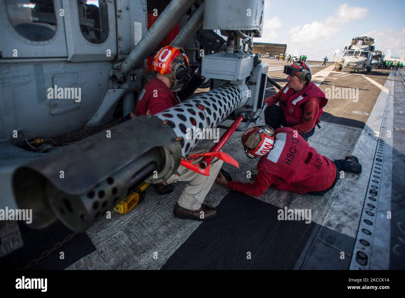 Les marins retirent un fusil de M197 20mm de la faucon MH-60s. Banque D'Images