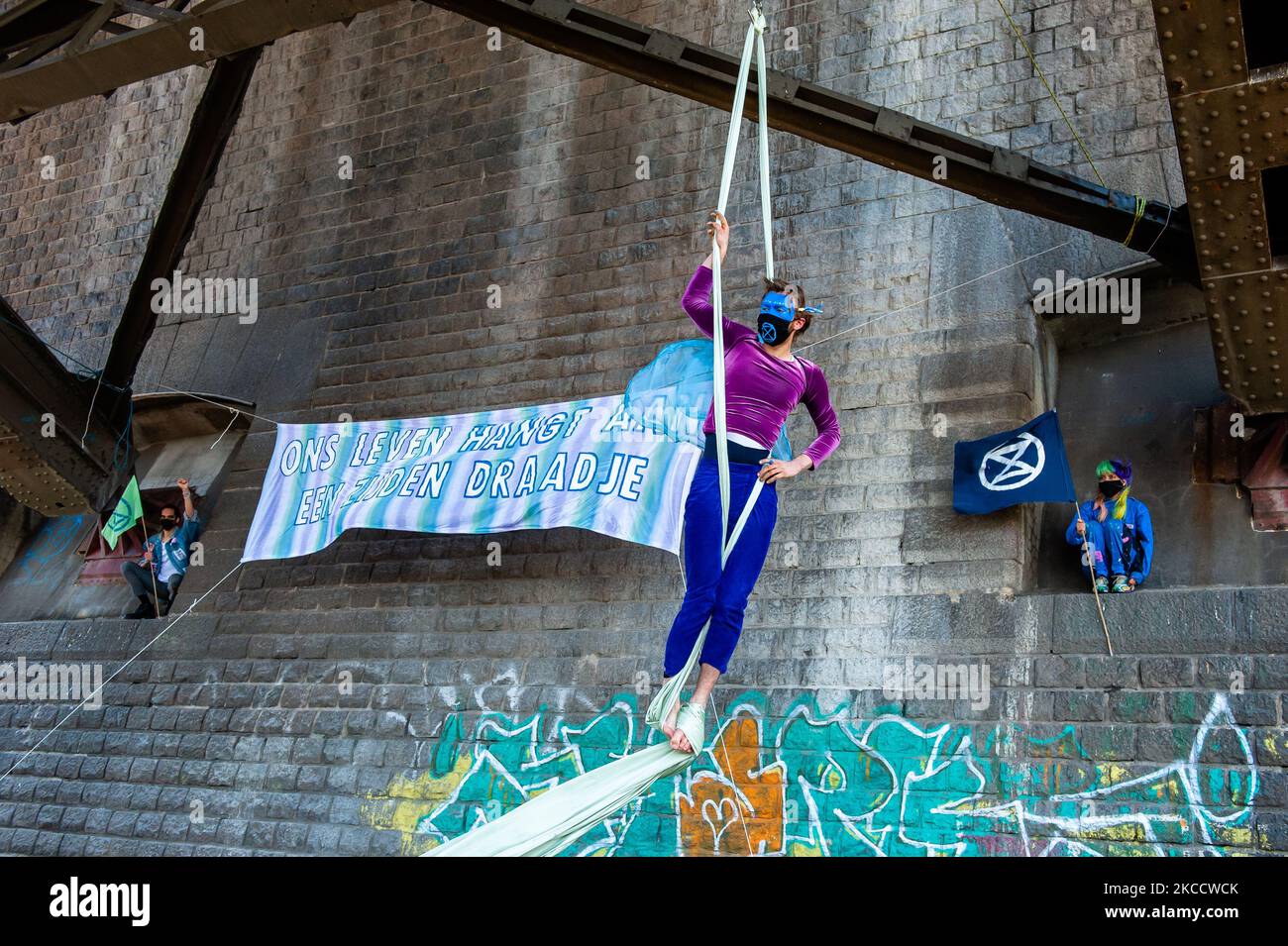 Un acrobat est en train de réaliser de la soie aérienne tandis qu'une bannière XR est suspendue derrière lui, au cours d'une action réalisée par la rébellion d'extinction à Nimègue, sur 16 avril 2021. (Photo par Romy Arroyo Fernandez/NurPhoto) Banque D'Images