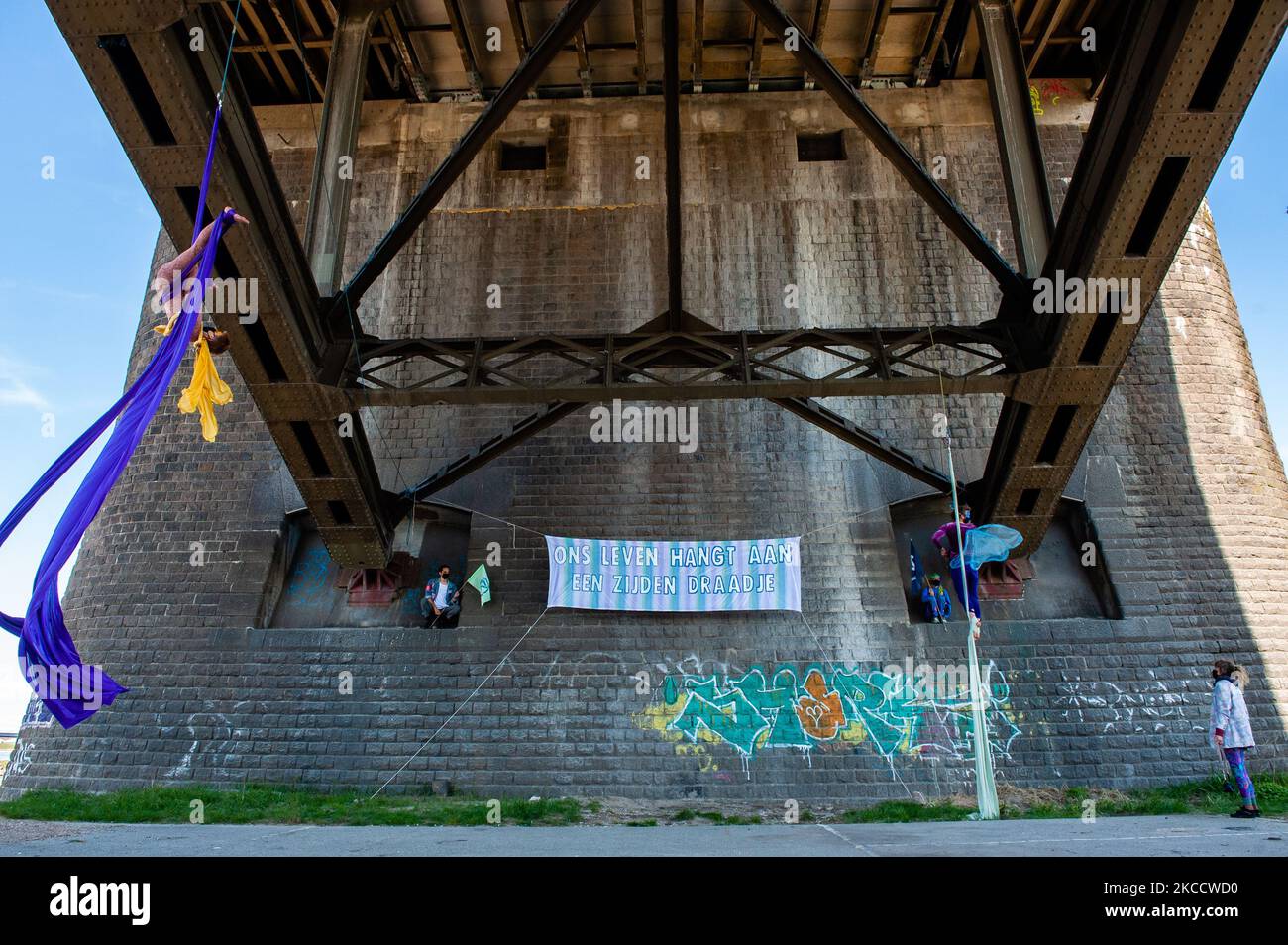 Deux acrobates se présentent avec de la soie aérienne sous un pont, au cours d'une action menée par la rébellion d'extinction à Nimègue, sur 16 avril 2021. (Photo par Romy Arroyo Fernandez/NurPhoto) Banque D'Images